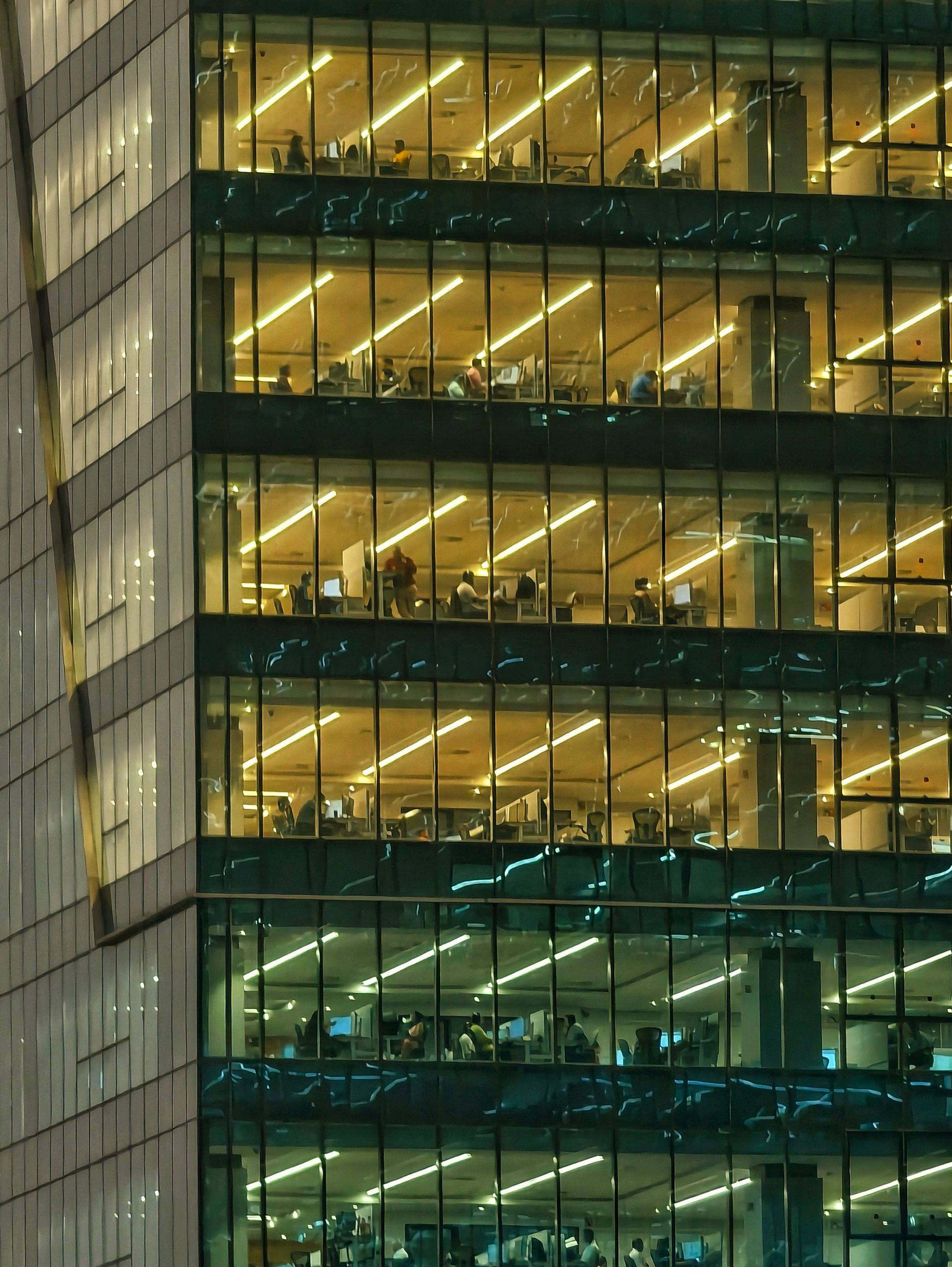 Modern office building in Hyderabad with glowing interior lights viewed at night, showcasing urban life.