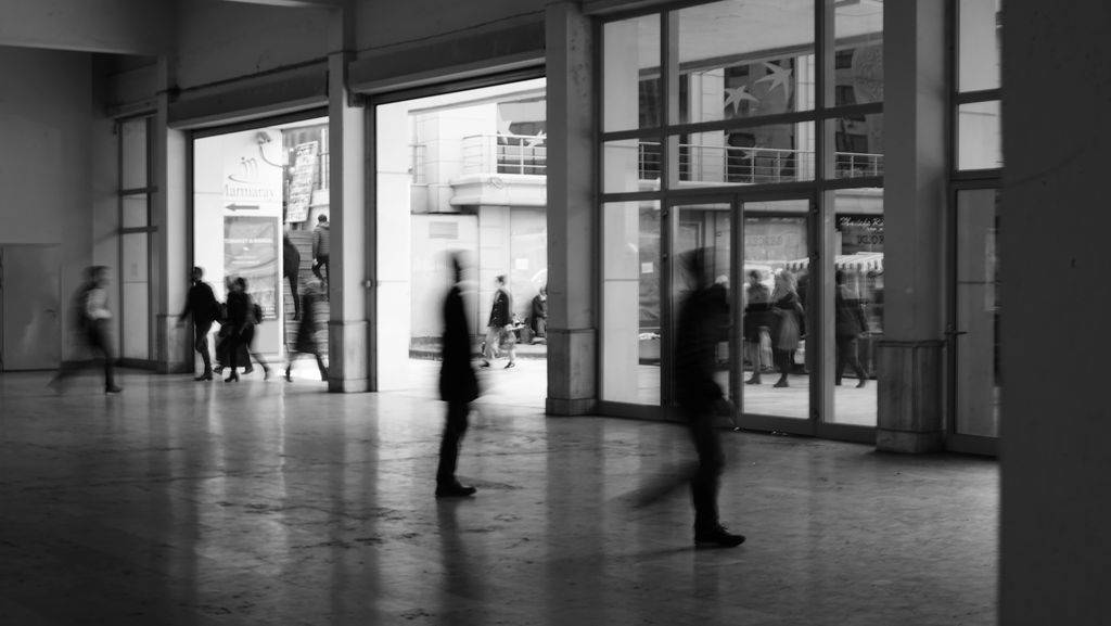 Black and white blurred rushing people walking in spacious public hallway of business center